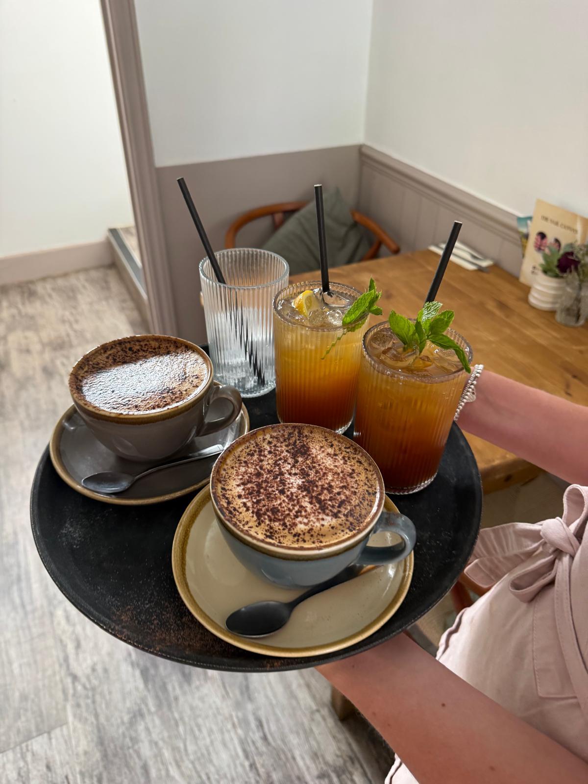 Cappuccinos and iced fruit teas on a serving tray