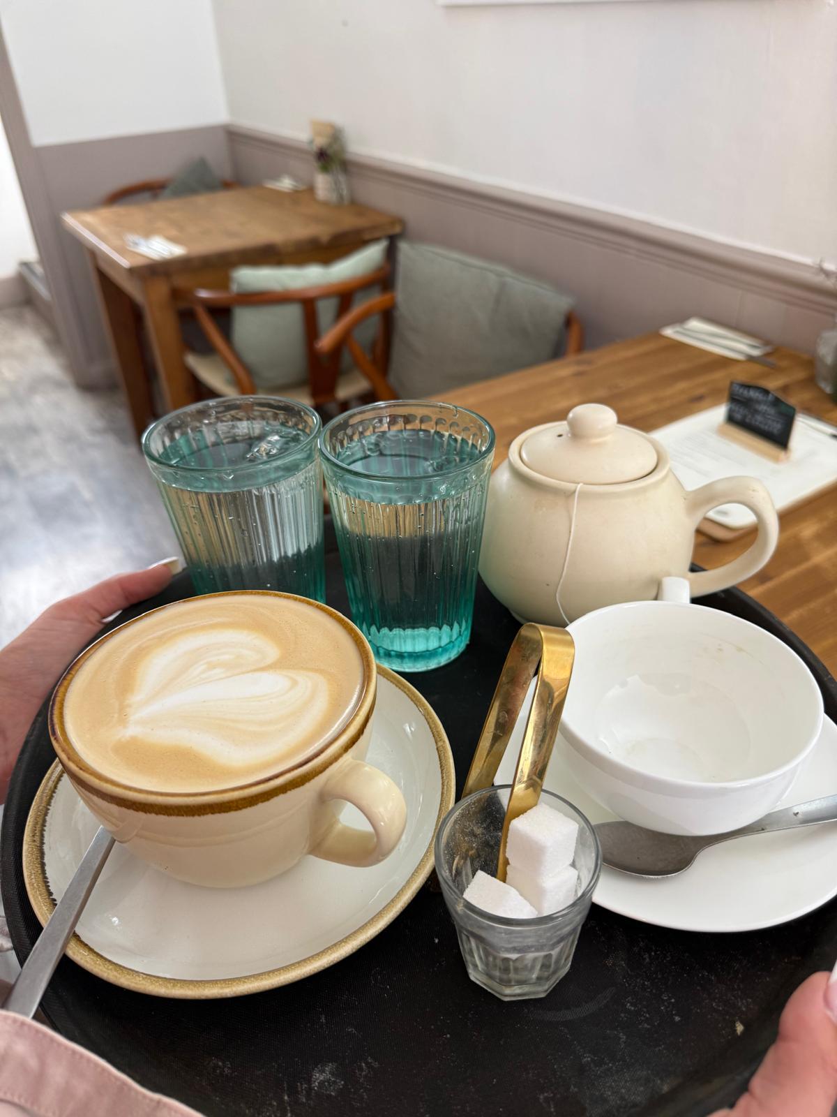Latte with teapot and water glasses on a tray
